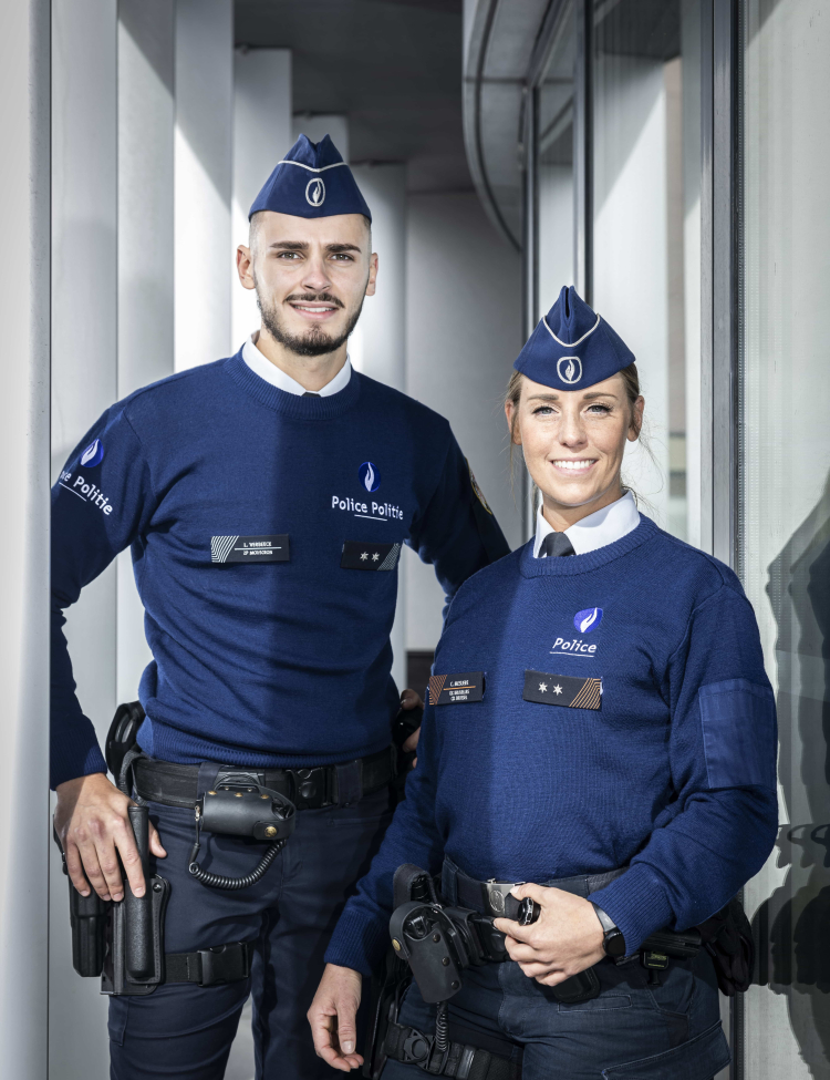 Vrouwelijke inspecteur en mannelijk inspecteur van de Federale Politie, poseren rug aan rug
