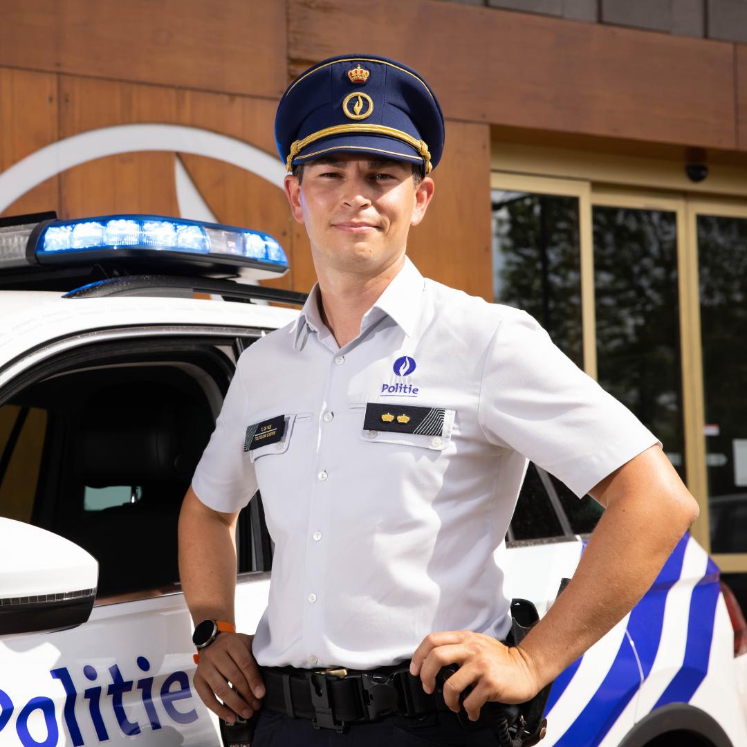 Mannelijke commissaris met képi aan politiewagen