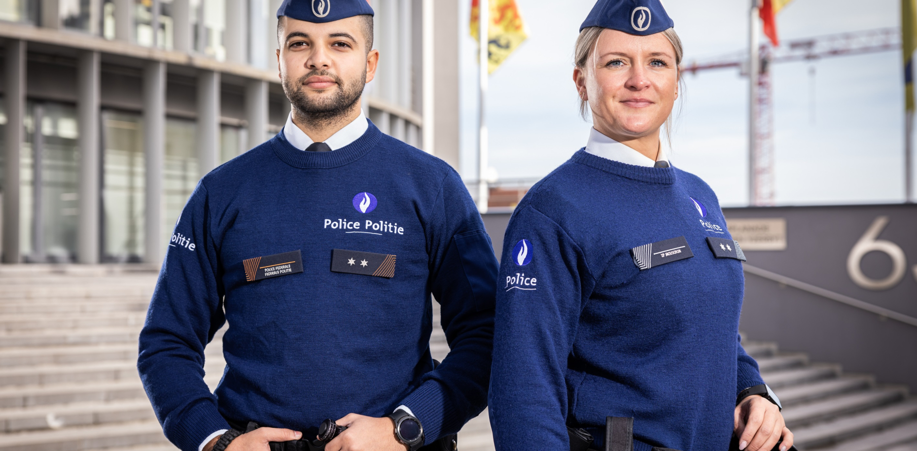 Een vrouwelijke en mannelijk inspecteur poserend rug aan rug